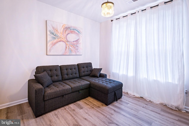 living room with a healthy amount of sunlight, light hardwood / wood-style flooring, and a notable chandelier