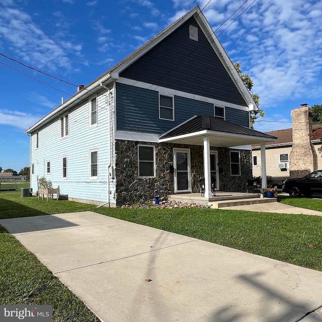 view of front of property with covered porch, a front lawn, and central air condition unit