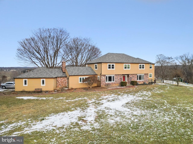 snow covered back of property featuring a lawn