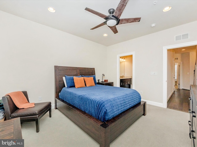 bedroom with light carpet, ensuite bathroom, and ceiling fan