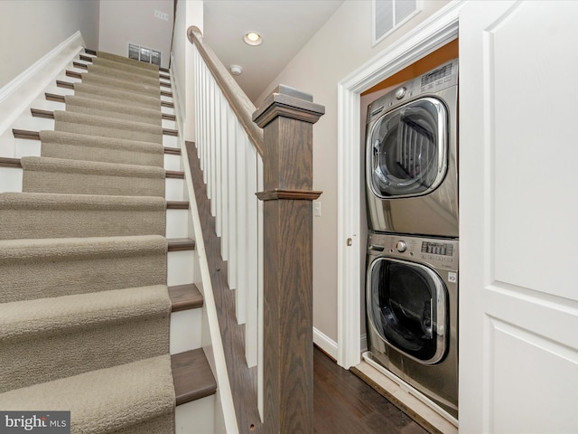 clothes washing area featuring dark hardwood / wood-style floors and stacked washer and clothes dryer