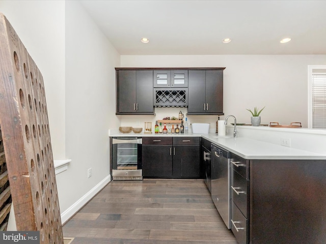 kitchen featuring dishwasher, sink, dark hardwood / wood-style flooring, kitchen peninsula, and beverage cooler