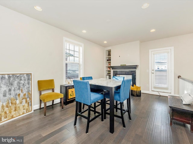 dining space with built in shelves, a healthy amount of sunlight, and dark hardwood / wood-style flooring