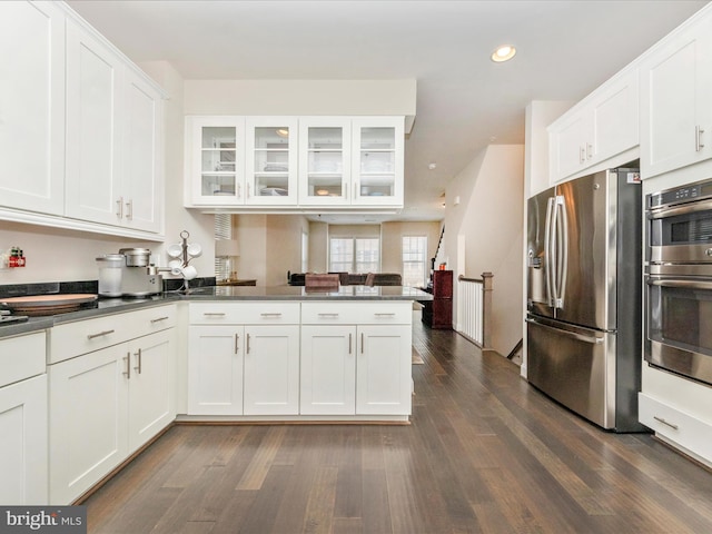 kitchen featuring dark hardwood / wood-style floors, white cabinetry, kitchen peninsula, and appliances with stainless steel finishes