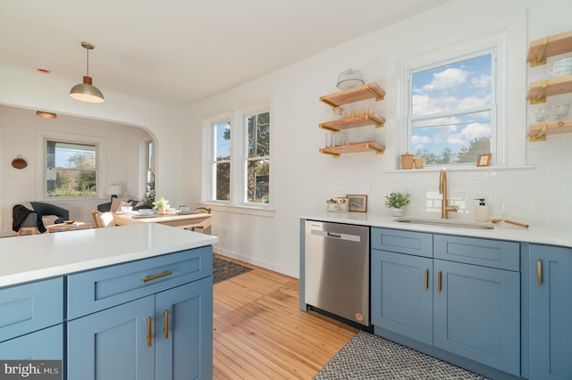 kitchen featuring dishwasher, sink, hanging light fixtures, and a wealth of natural light