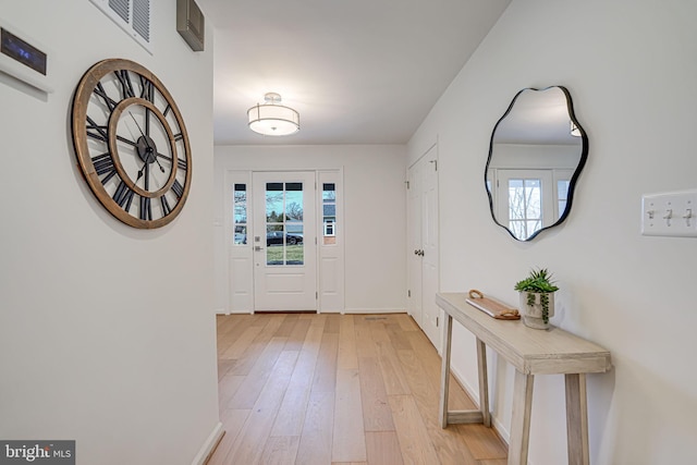 doorway to outside with visible vents, baseboards, and light wood-style flooring