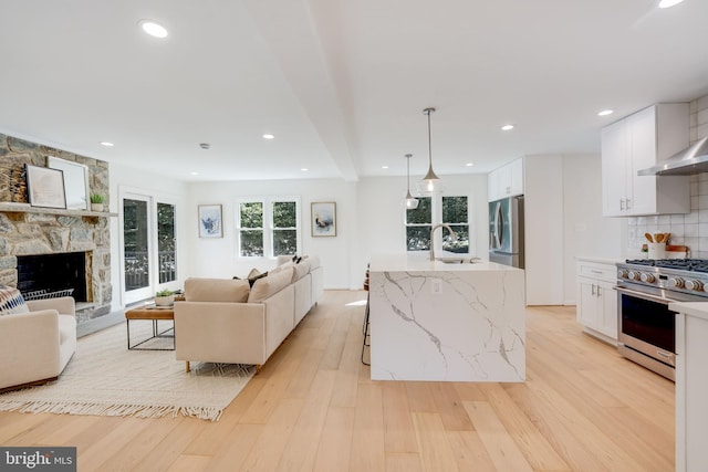 living room featuring a stone fireplace, recessed lighting, and light wood-style floors