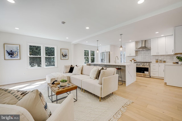 living room featuring recessed lighting, baseboards, and light wood-style floors