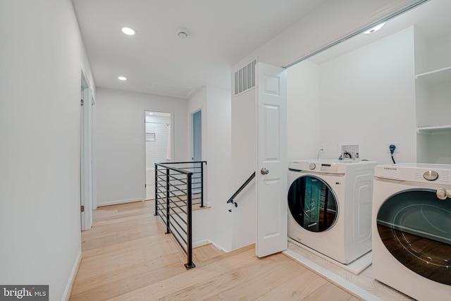 clothes washing area with visible vents, attic access, laundry area, light wood-style floors, and washer and dryer