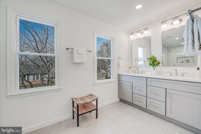 bathroom with a sink, baseboards, double vanity, and tile patterned flooring