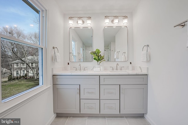 full bath with double vanity, baseboards, and a sink