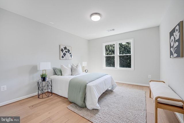 bedroom with baseboards, visible vents, and light wood-type flooring