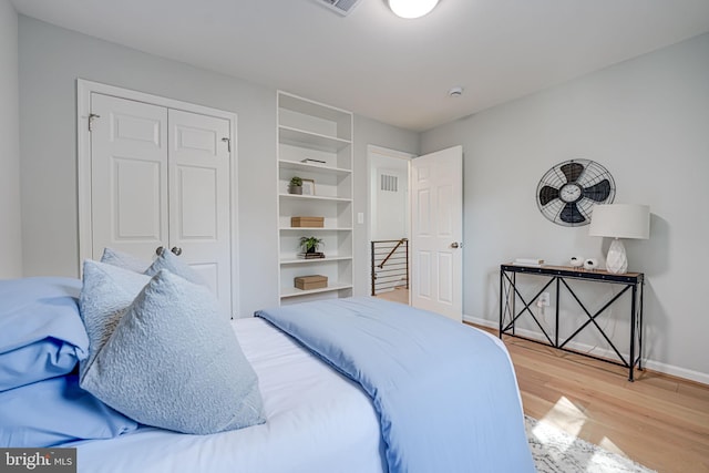 bedroom featuring a closet, visible vents, light wood-type flooring, and baseboards