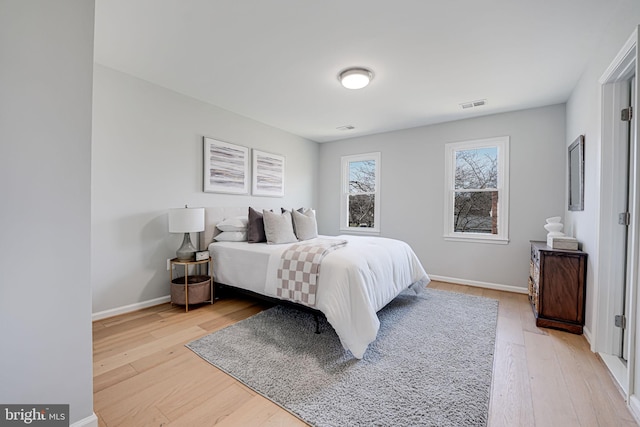 bedroom featuring light wood finished floors, visible vents, and baseboards