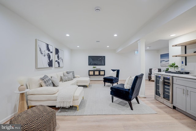 living area featuring beverage cooler, bar area, recessed lighting, light wood finished floors, and baseboards