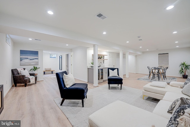 living area featuring light wood-style flooring, recessed lighting, beverage cooler, and visible vents