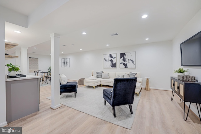 living room featuring recessed lighting, visible vents, light wood-style flooring, and ornate columns