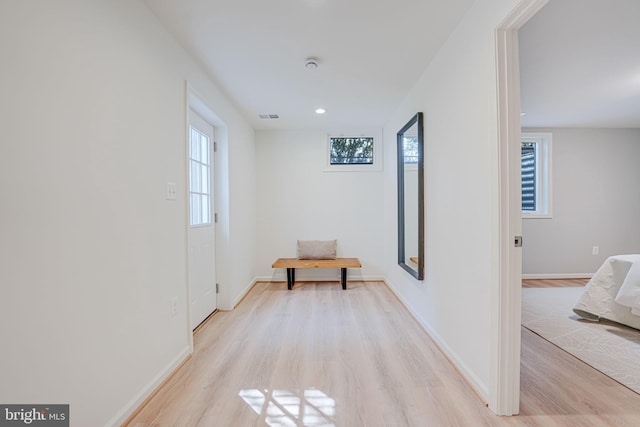 corridor featuring light wood-style flooring, recessed lighting, visible vents, and baseboards