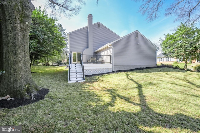 back of house with a deck, a yard, and a chimney