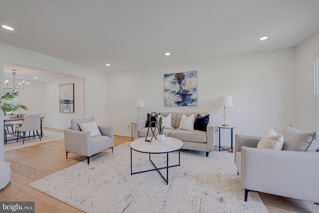 living room with recessed lighting, baseboards, an inviting chandelier, and light wood finished floors