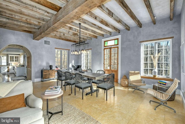 dining space featuring a wealth of natural light, beamed ceiling, and a chandelier