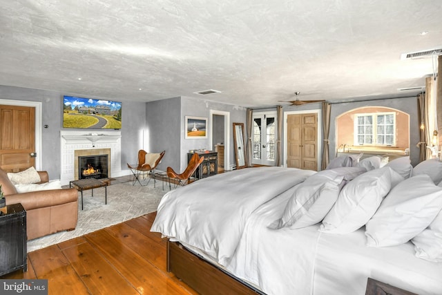 bedroom featuring a fireplace, wood-type flooring, and french doors