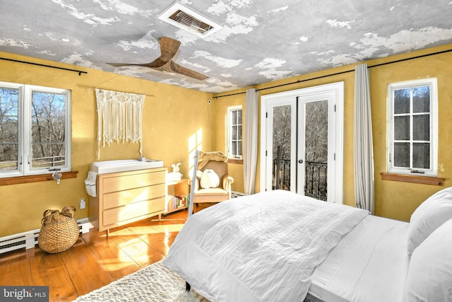 bedroom featuring ceiling fan, french doors, a baseboard radiator, hardwood / wood-style floors, and access to outside