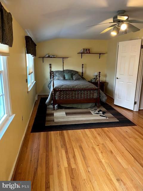 bedroom with hardwood / wood-style flooring, ceiling fan, and vaulted ceiling