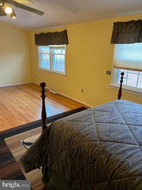 bedroom with multiple windows, hardwood / wood-style floors, and ceiling fan