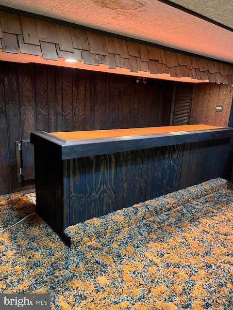 bar featuring a textured ceiling and wood walls