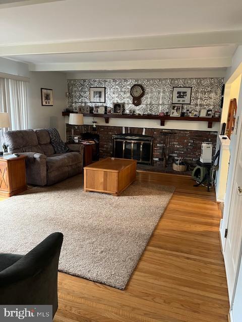 living room featuring hardwood / wood-style flooring, a fireplace, and beam ceiling