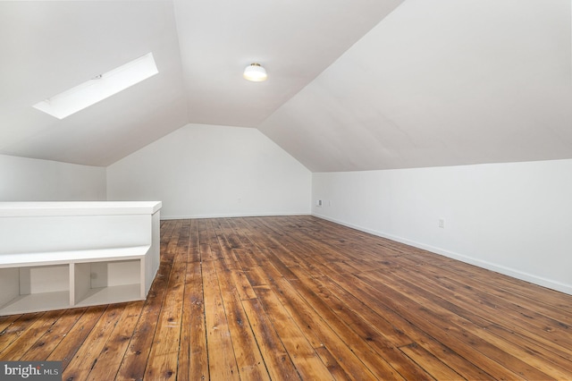 additional living space featuring lofted ceiling with skylight and dark wood-type flooring