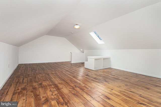 bonus room with wood-type flooring and vaulted ceiling with skylight