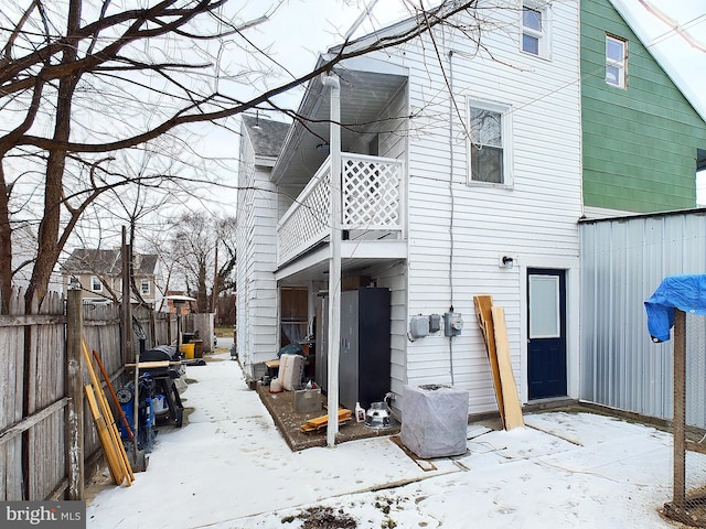 snow covered back of property with a balcony