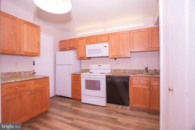 kitchen with hardwood / wood-style flooring, light stone countertops, white appliances, and sink