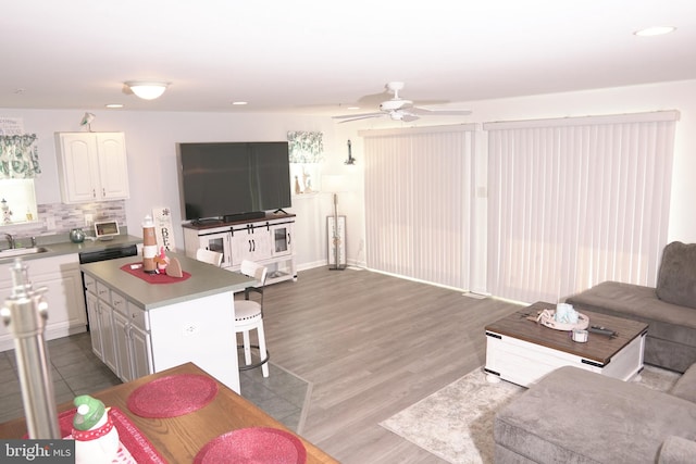 living room with ceiling fan, sink, and light hardwood / wood-style flooring