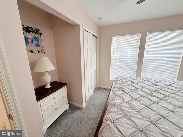 carpeted bedroom with ceiling fan, multiple windows, and a closet