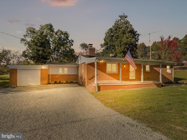 view of front of property with a garage, a lawn, and a porch