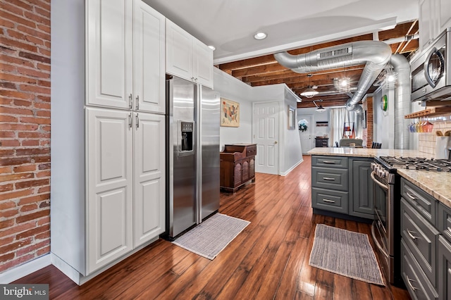 kitchen featuring gray cabinets, brick wall, white cabinets, light stone counters, and stainless steel appliances