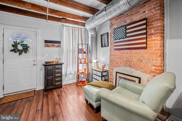 sitting room featuring a fireplace, wood-type flooring, and beam ceiling