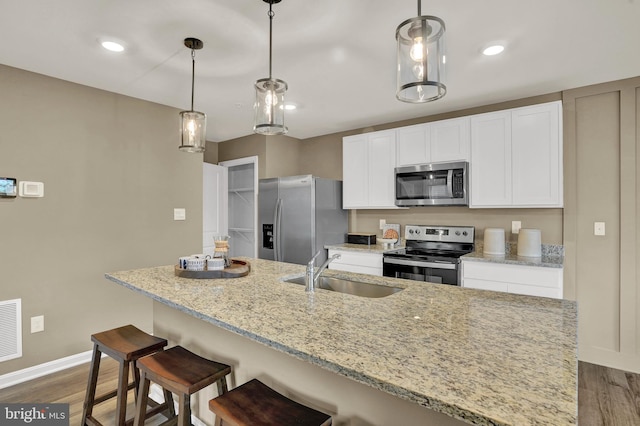 kitchen featuring white cabinetry, light stone countertops, sink, stainless steel appliances, and decorative light fixtures