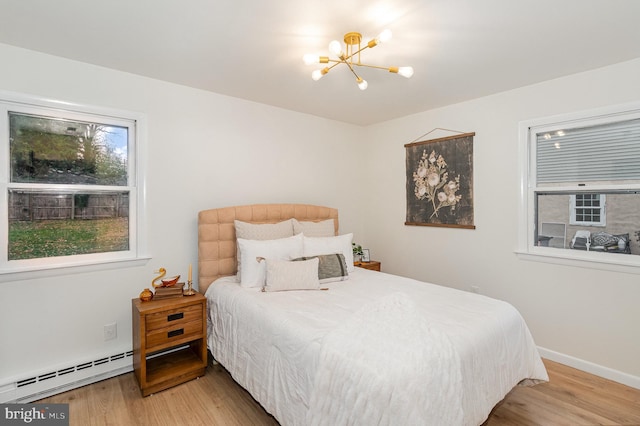 bedroom with wood-type flooring, a notable chandelier, and a baseboard heating unit