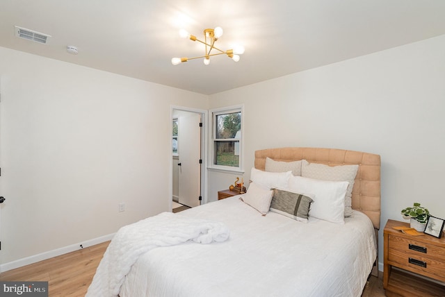 bedroom with hardwood / wood-style floors and a notable chandelier