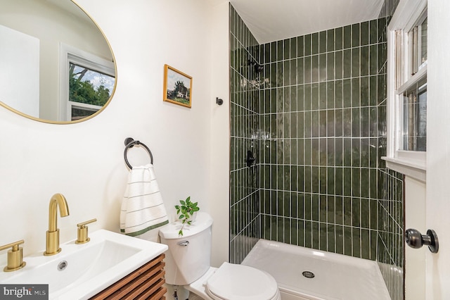 bathroom with vanity, toilet, and tiled shower