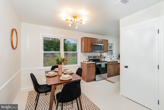 tiled dining area with sink, a chandelier, and plenty of natural light