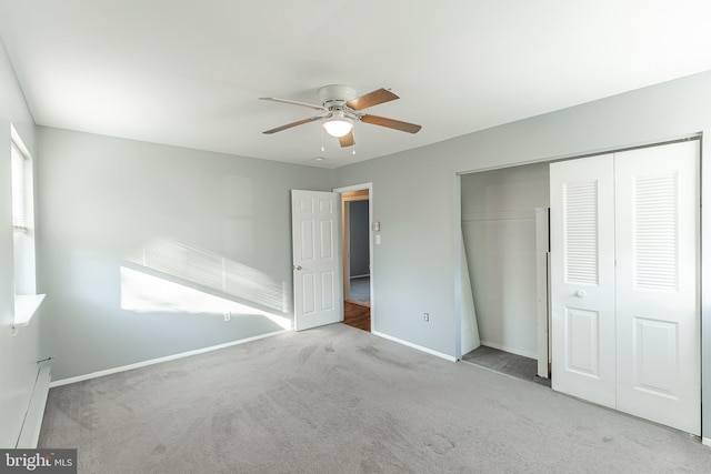 unfurnished bedroom featuring ceiling fan, a baseboard heating unit, light colored carpet, and a closet