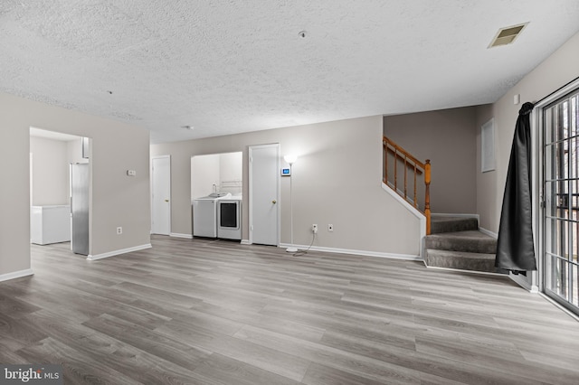 unfurnished living room featuring baseboards, visible vents, stairway, wood finished floors, and a textured ceiling