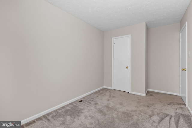 unfurnished bedroom with carpet floors, baseboards, and a textured ceiling