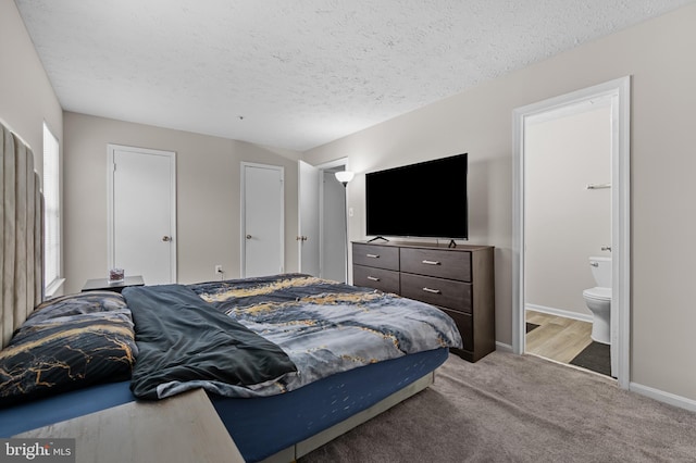 carpeted bedroom featuring a textured ceiling, ensuite bathroom, and baseboards