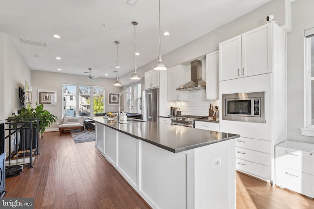 kitchen featuring a kitchen island with sink, white cabinets, ceiling fan, wall chimney exhaust hood, and high quality appliances